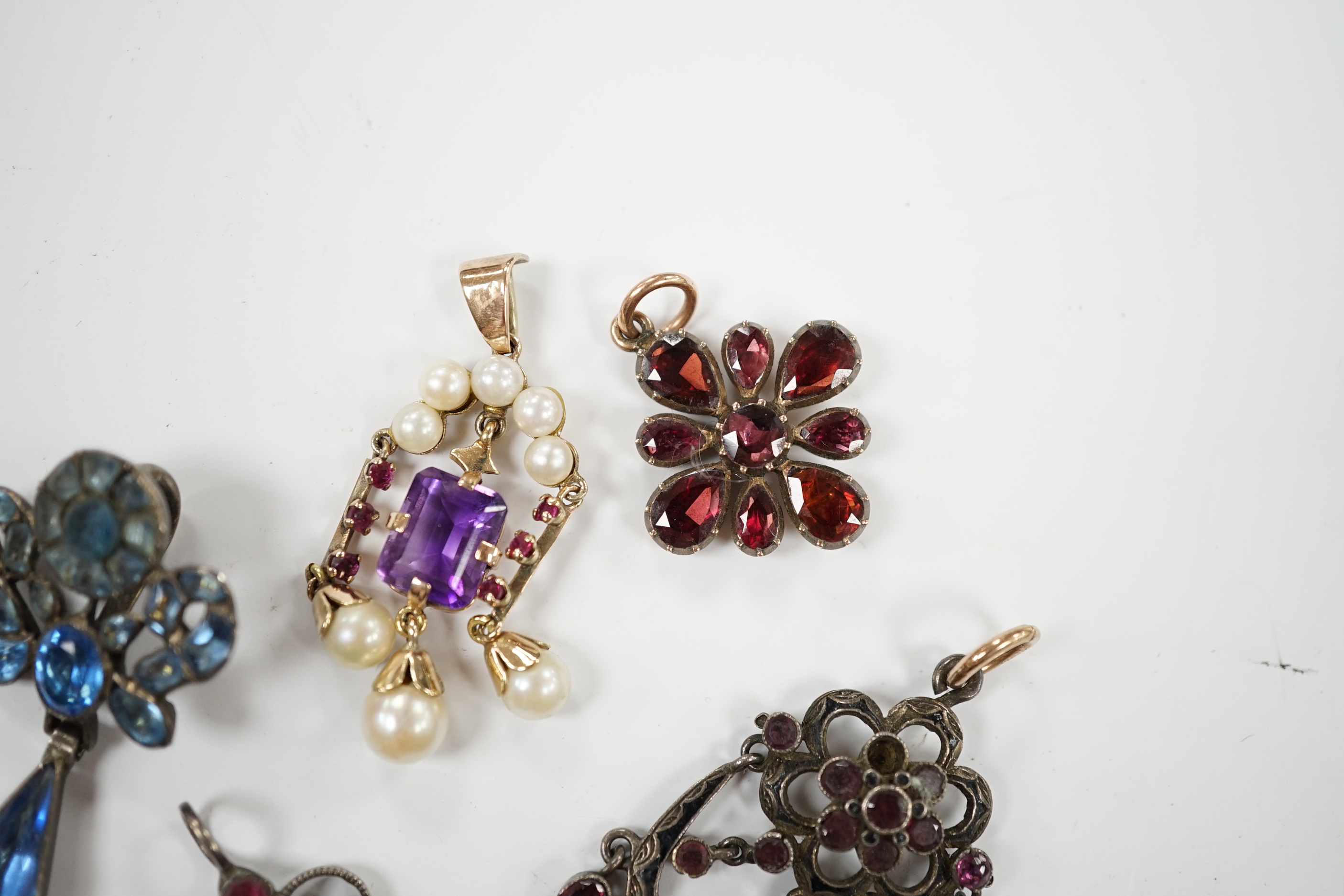 A Georgian yellow metal and foil backed garnet set cluster pendant, 26mm and four other later pendants.